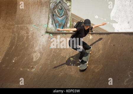 Femmina giovane guidatore di skateboard la pratica in skatepark all'aperto Foto Stock