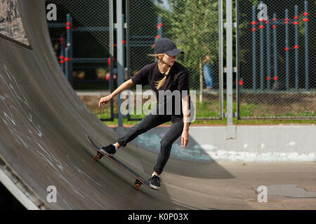 Femmina giovane guidatore di skateboard la pratica in skatepark all'aperto Foto Stock