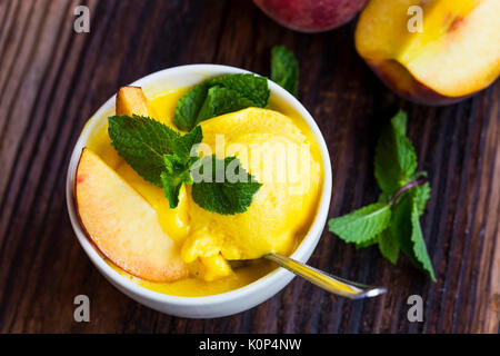 Pesca e mango sorbetto gustoso closeup con foglie di menta, dessert estivo Foto Stock