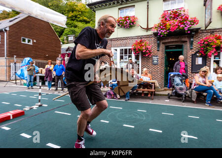 La popolazione locale "howjumping' con un cavallo giocattolo all annuale South Street la giornata dello sport e Dog Show, Lewes, East Sussex, Regno Unito Foto Stock