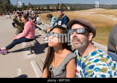 I visitatori di indossare occhiali protettivi a reagire come si guarda un eclisse solare totale a vecchie fedeli all'interno del Parco Nazionale di Yellowstone Agosto 21, 2017 a Yellowstone, Wyoming. L'eclisse totale spazzato attraverso una porzione ristretta di contigui Stati Uniti da Oregon a Carolina del Sud e una parziale eclissi solare era visibile in tutto il nord del continente americano insieme con alcune parti del Sud America, Africa ed Europa. Foto Stock