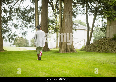Vista posteriore della donna che cammina nel campo Foto Stock