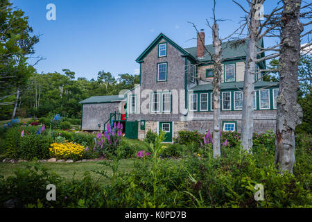 Un bel grigio e verde home con colore rosso brillante porta è un stile New England casa in Costa del Maine Foto Stock
