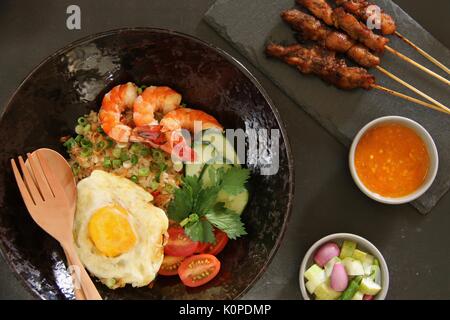 Nasi Goreng Gourmet, Indonesiana riso fritto con gamberetti, uovo e pollo Satay Foto Stock