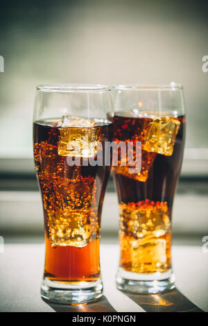 Bella bevanda fredda di cola con cubetti di ghiaccio in un vetro di un finestrino grigio Sfondo con spazio libero Foto Stock