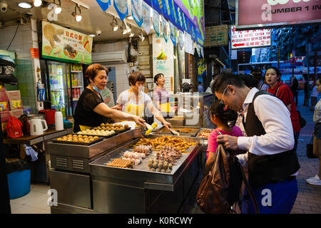 HONG KONG - Luglio 11, 2017: un venditore ambulante di vendita spuntini popolari a Fa Yuen Street, il mercato notturno in Kowloon. Questi includono stinky tofu, intestino del maiale Foto Stock