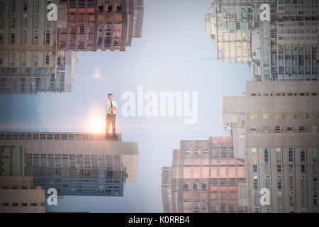 Imprenditore bello sorridente in telecamera contro moderni grattacieli in città Foto Stock