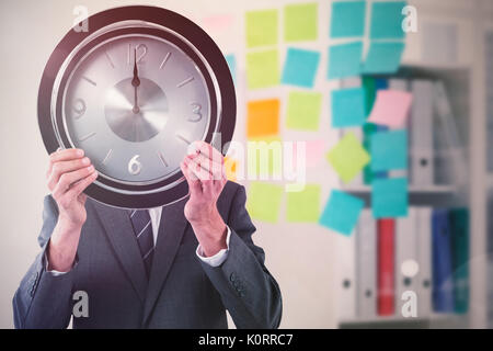 Imprenditore orologio di contenimento nella parte anteriore del suo volto contro closeup di coloratissimi sticky notes in ufficio Foto Stock