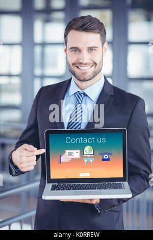 Contattaci il testo con icone contro happy businessman mostrando laptop Foto Stock