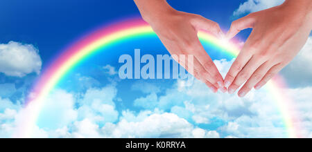 Donna messa a forma di cuore con le mani contro la visione idilliaca di nuvole contro sky Foto Stock
