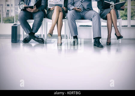 La gente di affari in attesa di essere chiamato in colloquio presso l'ufficio Foto Stock
