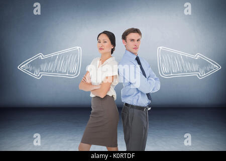 Colleghi di lavoro con le braccia incrociate in ufficio contro camera grigia Foto Stock