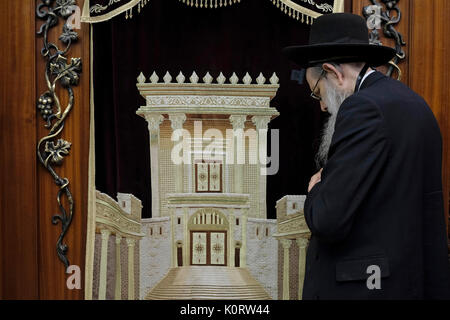 Un Ebreo adoratore pregando accanto alla Torah Arca armadio che contiene la Torah ebraica scorre decorata con una figura che illustra il biblico tempio ebraico all'interno di uomini della sezione di Wilson's Arch presso il Muro Occidentale composto nella città vecchia. Gerusalemme Est, Israele Foto Stock