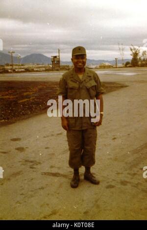 Una piena lunghezza Ritratto di tenente dell'esercito al Walker, che posano per una foto in una postura rilassata e con un sorriso, di fronte all'elipad a Danang supportano il comando, Vietnam, 1964. Foto Stock