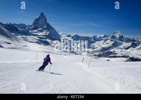 Sciatore femmina sciare solo sulla pista da sci verso monte Cervino in una giornata di sole in località sciistica di Zermatt, canton Vallese in Svizzera. Foto Stock