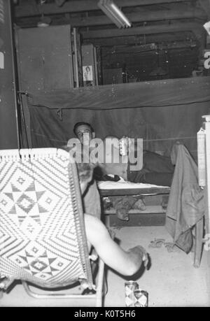 Una fotografia di due esercito degli Stati Uniti del veterano della socializzazione nella loro caserma, un soldato è sdraiato sul letto e tenendo una lattina di Coca Cola, un altro veterano si siede in un prato sedia e ha diverse lattine di coca sul terreno accanto a lui, Vietnam, 1967. Foto Stock