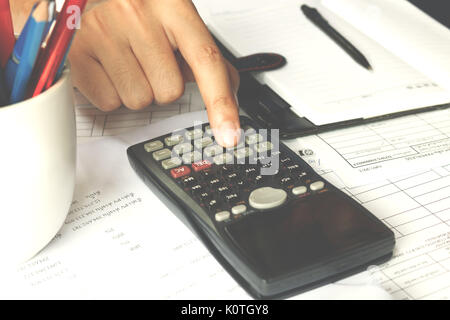 Dati finanziari l'analisi. Close-up foto di un imprenditore il conteggio a mano sulla calcolatrice in ufficio. Soft focus Foto Stock