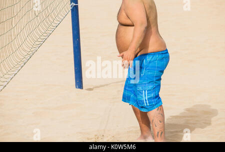 Il sovrappeso uomo giocando a pallavolo sulla spiaggia in Spagna Foto Stock