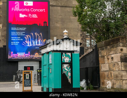 Edimburgo, Scozia, Regno Unito. 25 Agosto 2017. Sono in corso i preparativi per l'ultimo fine settimana dei Festival di Edimburgo, che si concluderanno con il Virgin Money Festival Fireworks a Princes Street Gardens sotto lo sfondo del Castello di Edimburgo. Grande poster elettronico che pubblicizzano i fuochi d'artificio del Festival con una Call Box di polizia decorata a Leith Walk Foto Stock