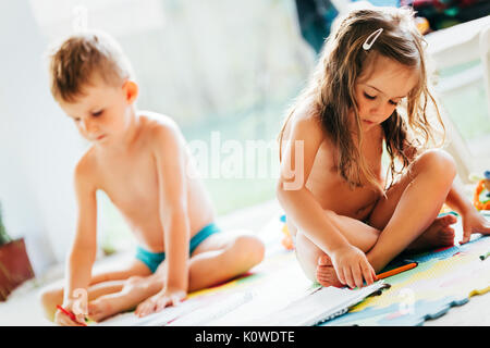 Piccolo Ragazzo e ragazza di Disegno con matite colorate Foto Stock