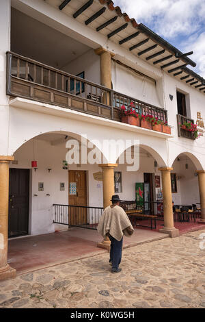 Luglio 13, 2017 Villa de Leyva, Colombia: un uomo che indossa il poncho tradizionali passeggiate in un edificio coloniale nel centro storico Foto Stock