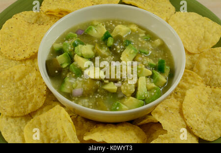 Close up di avocado e tomatillo salsa verde guacamole miscela con round tortilla chips su piastra Foto Stock