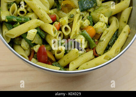 Chiudere fino al pesto penne insalata di pasta con zucchine, pomodori e fagioli verdi e mozzarella nel recipiente di miscelazione Foto Stock