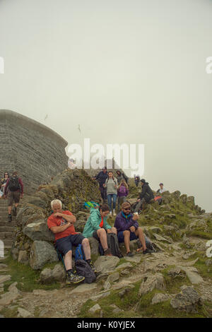 La Folla di escursionisti in appoggio e tenendo la vista dalla cima di Mount Snowdon Foto Stock