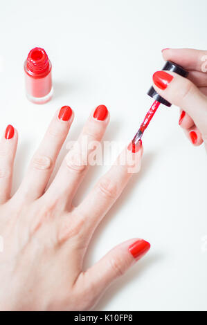 Giovane donna è la pittura i suoi chiodi con rosso smalto per unghie Foto Stock