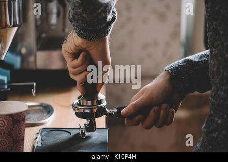 L'uomo timbratura appena macinato di caffè del mattino Foto Stock