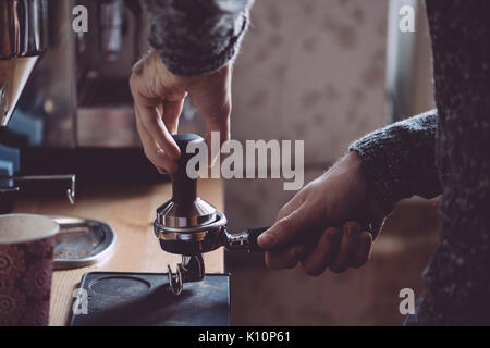 L'uomo timbratura appena macinato di caffè del mattino Foto Stock