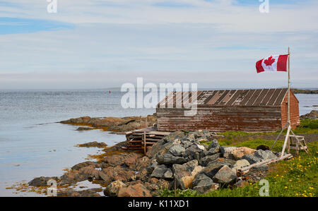 Bandiera canadese battenti accanto alla cabina di legname, l'Anse aux Meadows, Grande Penisola Settentrionale, Terranova, Canada Foto Stock