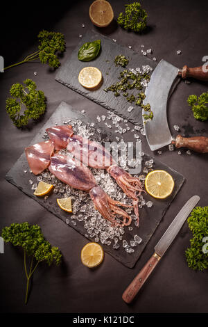 Crudo fresco calamari con ghiaccio tritato e limone Foto Stock