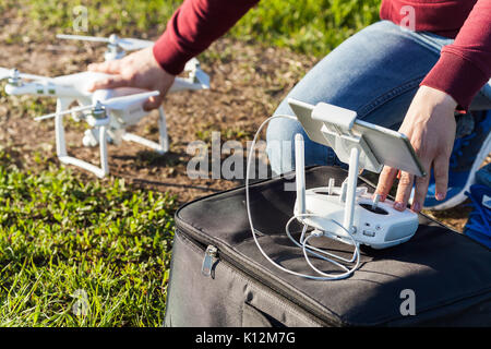 Voli quadcopter all'aperto, immagini aeree e tech hobby concetto - la preparazione per il lancio di un drone su un prato estivo con erba verde, maschio mani di pilo Foto Stock