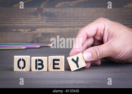 Obbedire da lettere di legno su sfondo di legno Foto Stock