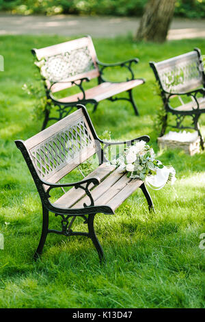 Fiori e piante ornamentali, il concetto di matrimonio. bel bouquet della sposa bianco con nastro di seta giacente sul brown panchina da giardino dimenticato Foto Stock