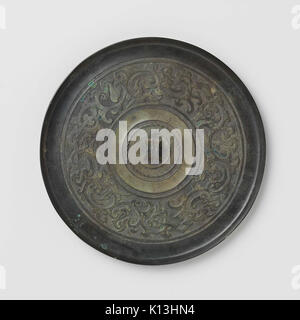 Uno specchio caratterizzato da motivi stilizzati di uccelli e draghi, progettato con motivi intricati e creature mitiche, che combinano arte e artigianato nella sua forma decorativa. Foto Stock