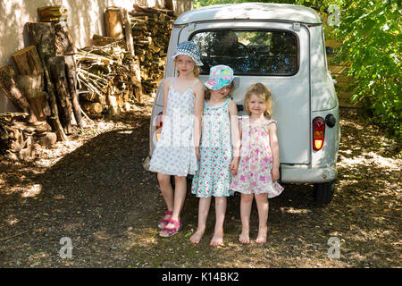 Tre giovani ragazze francesi di età compresa tra i 3, 5 e 7 anni: la prossima generazione di automobilisti, appoggiarsi contro un vintage Renault 4L auto appartenenti alla loro nonna. Foto Stock