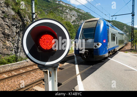 Treno veloce e un segnale di traffico rosso mostra / lampeggiante / luci di avvertimento per le auto a una ferrovia francese ferrovia ferrovia automatica passaggio a livello in Francia. Foto Stock