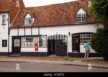 L'uomo pittura le finestre del vecchio ufficio postale in high street Dorchester on Thames Oxfordshire un vecchio nero e bianco edificio Foto Stock