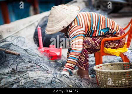 Donna vietnamita riparazione rete da pesca Foto Stock