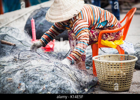 Donna vietnamita riparazione rete da pesca Foto Stock