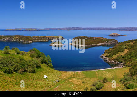 Verde mare con roulotte, piccole isole rocciose e la gamma della montagna di distanza, drumbeg, Sutherland, SCOZIA Foto Stock