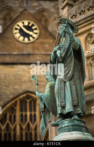 Statua religiosa di San Aldhelm suona l'arpa sul Digby Memorial al di fuori della chiesa abbaziale di Santa Maria Vergine (Sherborne Abbey), Sherborne, Dorset Foto Stock