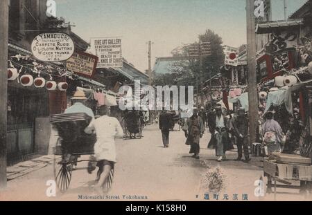 Una cartolina creata da una fotografia oscurata, una strada molto trafficata popolato da persone in viaggio a piedi e con i carrelli, aziende come rug e i commercianti di opere d'arte sono pubblicizzati, Yokohama, Giappone, 1912. Dalla Biblioteca Pubblica di New York. Foto Stock