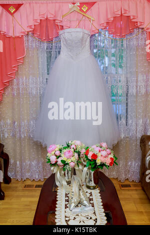 Il matrimonio perfetto vestito con un mantello completo su un appendiabiti in camera Foto Stock