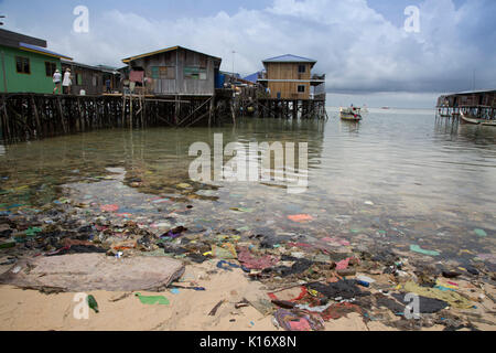 Immondizia di plastica e di altri rifiuti per un brutto spiaggia sulla scena Mabul Isola, Borneo. Le costruzioni in legno su palafitte sono bilancio dive resorts Foto Stock