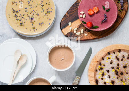 Diverse materie sano cheesecake, fatti in casa con la lavanda e menta e fragole. Tavolo per la colazione con una bevanda calda. Vista superiore Foto Stock