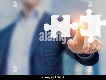 Fusioni e acquisizioni concetto con consulente toccando le icone dei pezzi di un puzzle che rappresenta la fusione delle due imprese o joint venture, partnershi Foto Stock