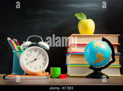 Accessori per la scuola sulla tavola con sfondo blackboard Foto Stock